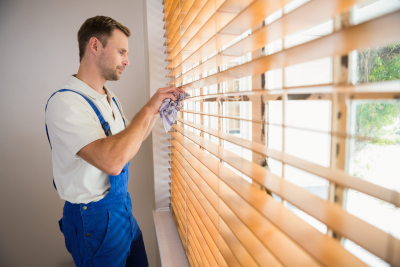 Handyman cleaning blinds with a towel in a new house