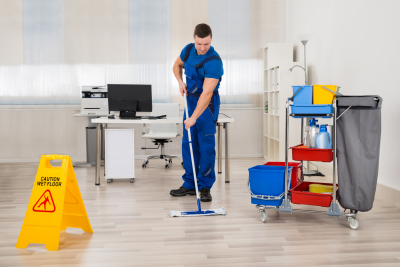 Full length of male janitor mopping floor in office