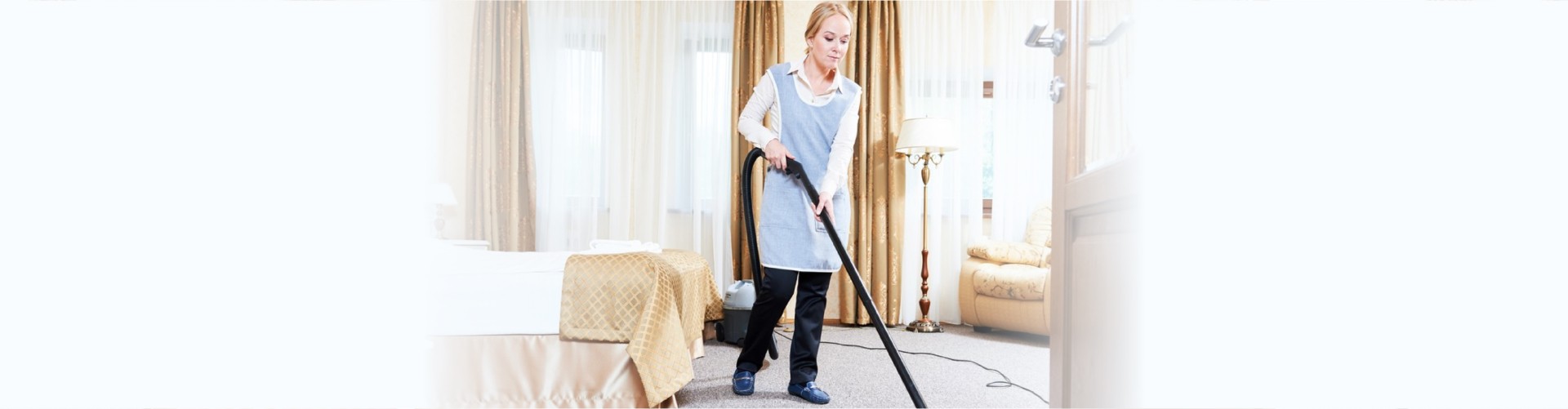 female housekeeping maid worker with vacuum cleaner in room apartment